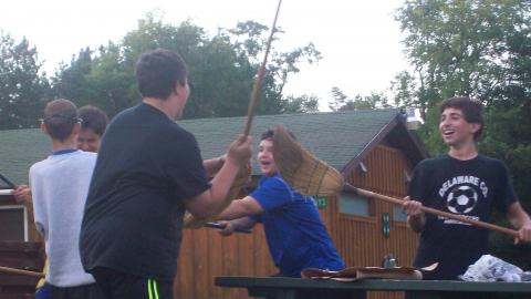 Campers playing a silly game using brooms. 