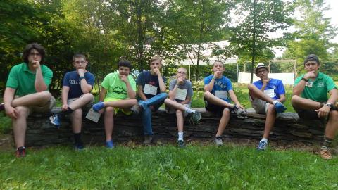 Campers and their counselors posing and sitting on a log. 