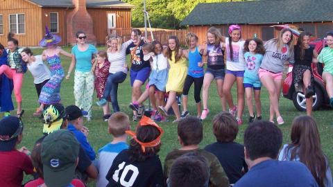 Youth doing a line dance in the field at camp. 