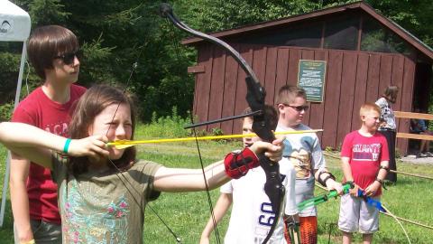 Campers prepare to shoot bow and arrows outside of camp. 
