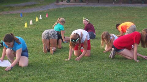 Youth searching for objects in the grass. 