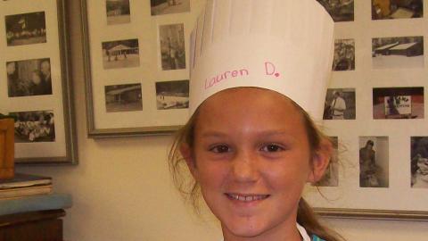 camper holding culinary creation and wearing a chef's hat.
