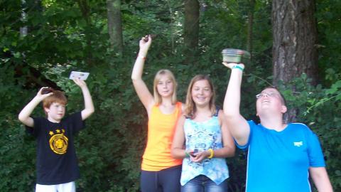 Youth hold up geocaching finds. 