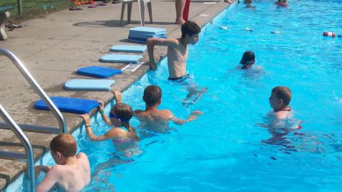Campers in the pool waiting to begin a swimming lesson. 