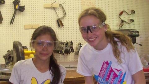 Two youth working on wood shop projects and smiling. 