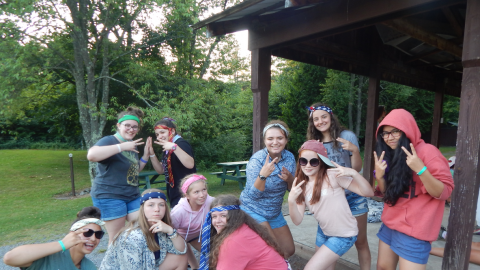 Cabin group wearing bandannas or ties around their heads and making peace signs as a group.
