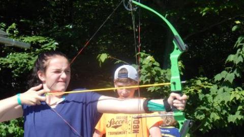 Campers shooting bow and arrows. 