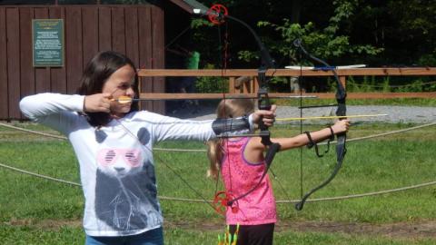 Campers shooting bow and arrows. 