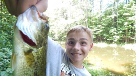 Youth smiling holding a large fish near the camera.