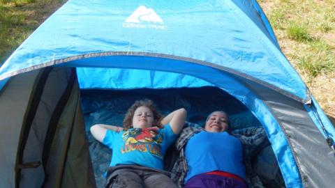 Youth lay down in a tent ready for backpacking. 