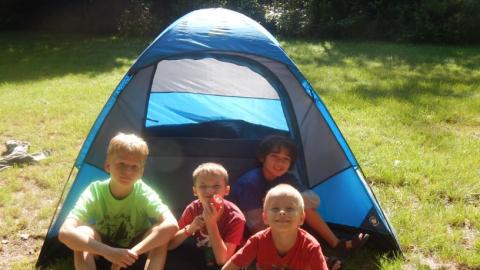 Campers sit in front of their tent. 