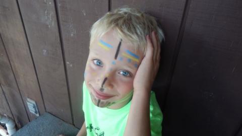 Youth with face painted is smiling for the camera. 