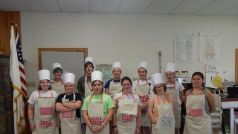 Campers pose for a photo with their chef aprons and hats on. 