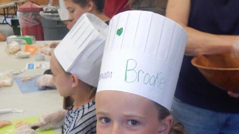Youth wearing a chef's hat and smiling. 