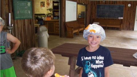 Campers playing a game with shower caps and Cheetos.