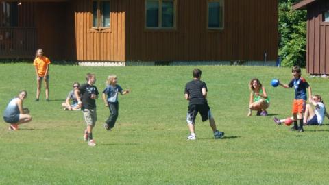 Campers play dodge ball in the field at camp. 