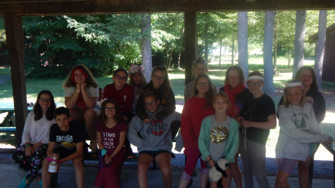 Group of campers seated on picnic tables posing for a photo together.