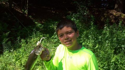 Youth holds up a freshly caught fish. 
