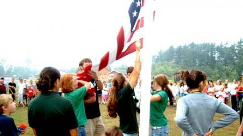 campers and counselors gathered together to raise the American flag.