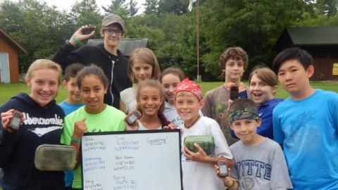Youth holding up their geocaching equipment. 