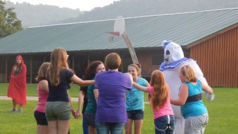 Youth playing a game with someone dressed in a blow-up costume. 