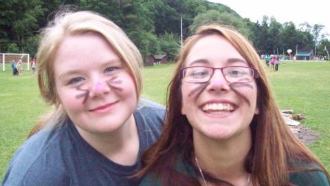 Youth wearing cat face paint and smiling. 