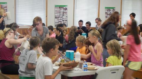 Campers pass food along the table at mealtime. 