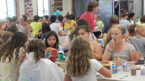 Campers eating a meal at tables in the dining hall. 