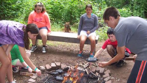 Youth cooking on an open campfire. 