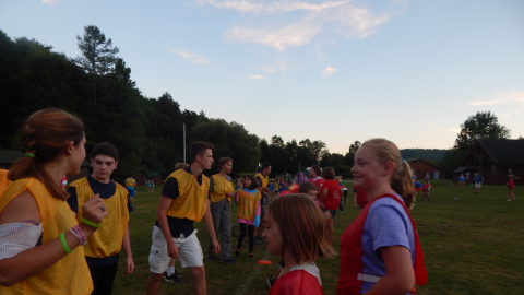Two opposing teams of youth and counselors face each other at a divider marked with frisbees.