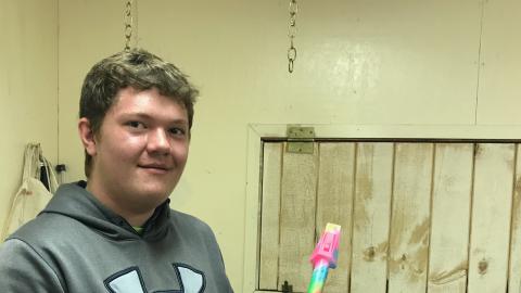 Teen holding a completed model rocket that has been painted tie-dye colors.