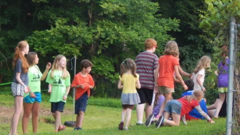 Campers search for objects in the grass. 
