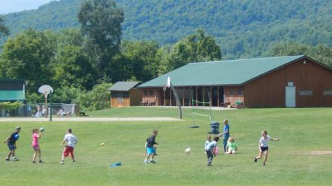 Youth playing a ball game in the field at camp. 