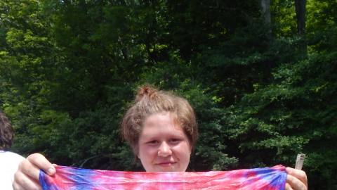 Camper holding up a freshly rinsed tie-dye bandanna.