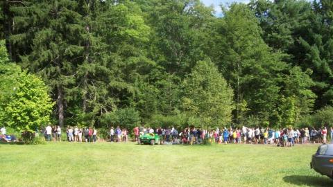 Campers and counselors in the distance planting a tree. 