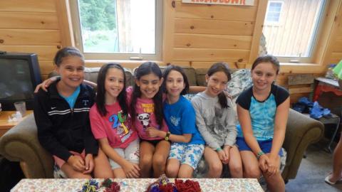 Campers sitting on couch in front of a table with yarn on it 