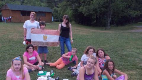 campers pose with Egyptian flag while others sit on the ground in front of them
