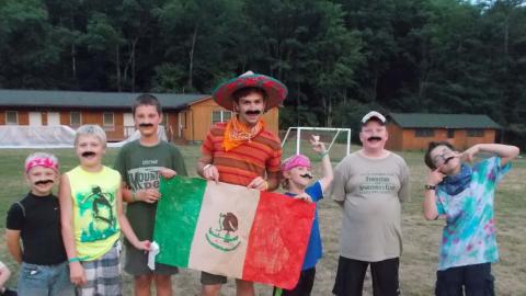 campers posing with handmade Mexican flag wearing fake mustaches.