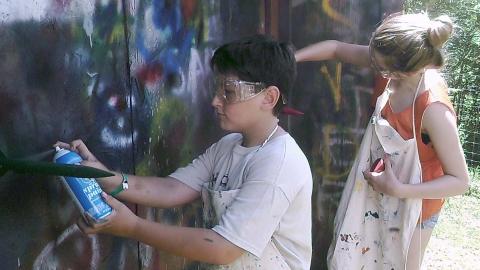 campers spray paint model rockets outside wearing aprons and safety googles 