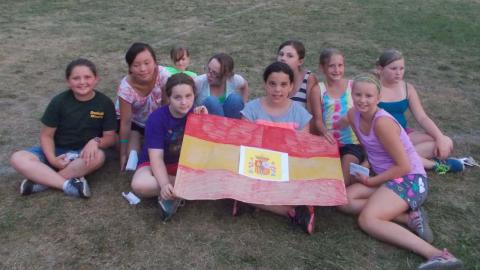 campers sitting on the ground and holding a Spanish flag 