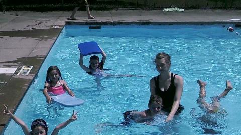 campers swim with counselor and use kick boards 