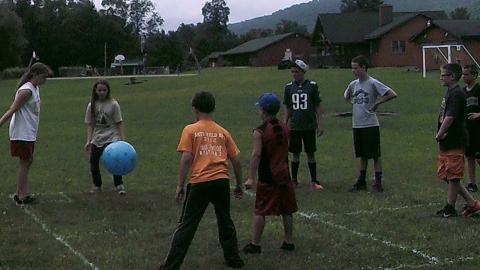 Campers standing on grass playing with large rubber ball