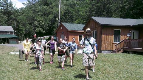 campers walk behind a counselor carrying exercise mats 