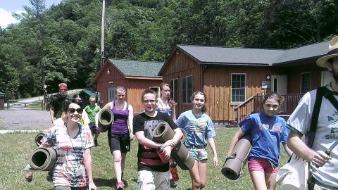 campers holding exercise mats and following counselor 